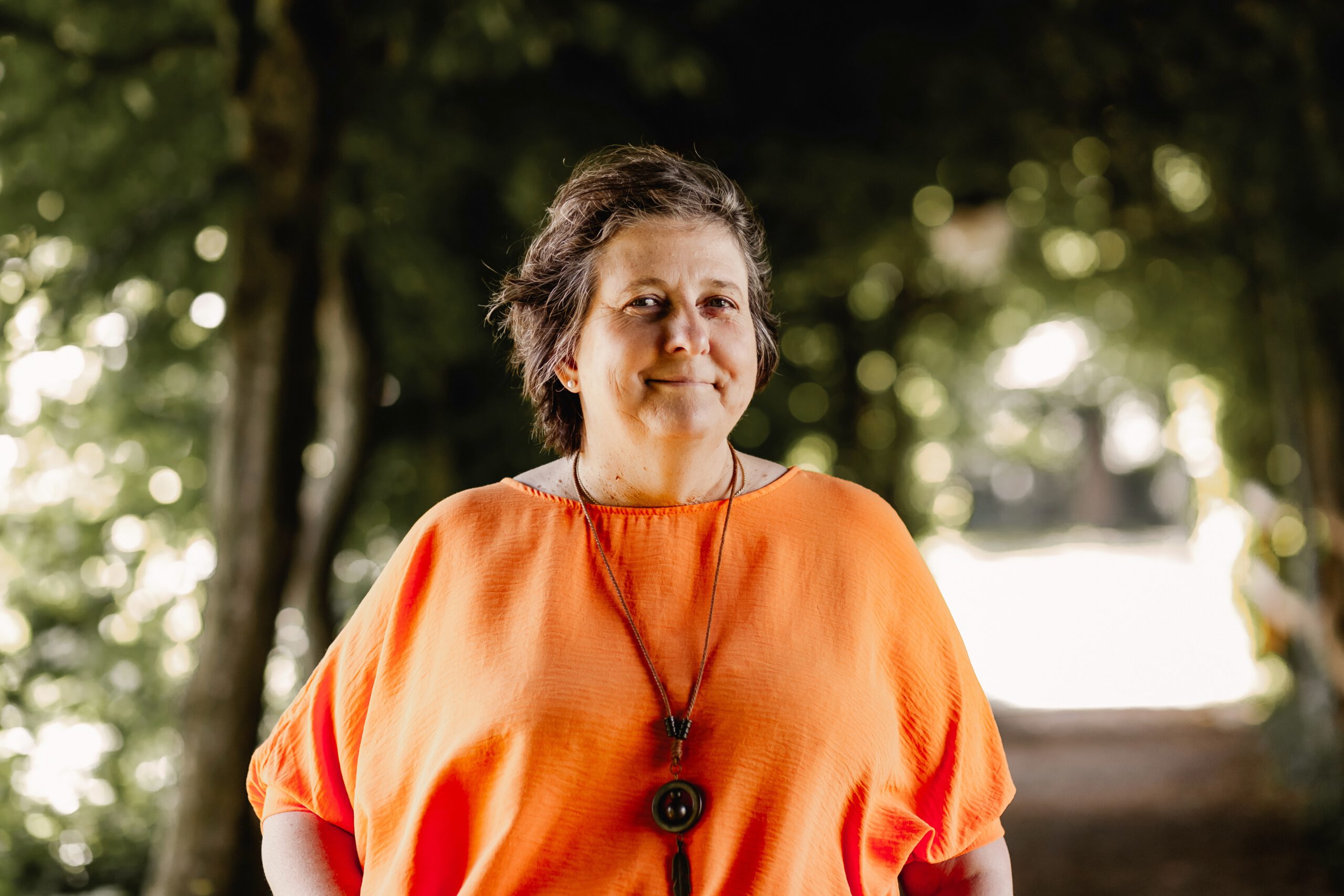 Symbolbild - Edith Baur mit einem Lächeln auf einem Weg im Wald
